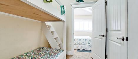 Un dormitorio con una litera, una puerta y una escalera.