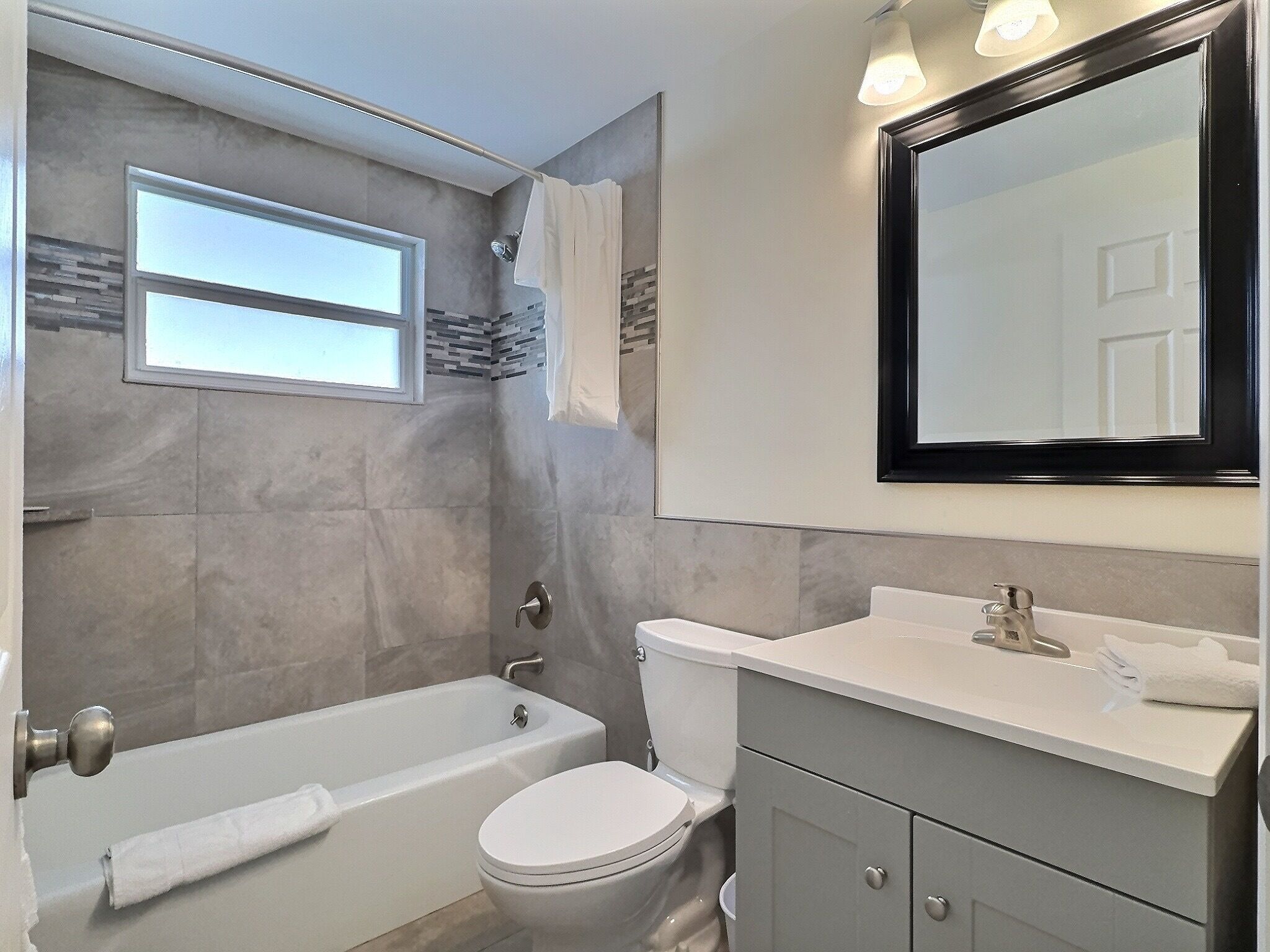 A modern bathroom with a bathtub, toilet, and vanity.