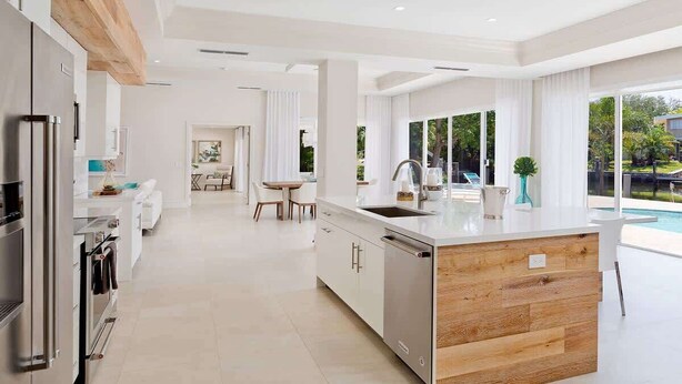 Cocina moderna con una isla de madera, electrodomésticos de acero inoxidable y vista a una piscina.