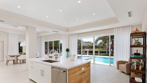 Una cocina amplia con una isla grande, comedor y vistas a una piscina.