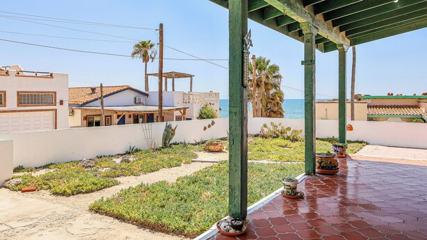 A covered outdoor area with a patio, plants, and a view of the sea.