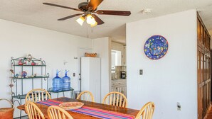 A dining area with a wooden table, chairs, a ceiling fan, and a decorative plate on the wall.