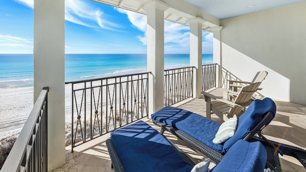 A balcony with a view of the beach and ocean, furnished with lounge chairs and a table. - Frangista Tide*All New Furnishings*Pool*BeachSvc+Gear (Miramar Beach)