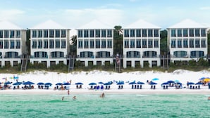 A beachfront hotel with multiple balconies, a sandy beach, and several umbrellas. - Frangista Tide*All New Furnishings*Pool*BeachSvc+Gear (Miramar Beach)