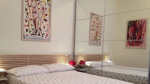 Ein Hotelzimmer mit zwei Betten, jeweils mit einem blumengemusterten Überwurf, einem hölzernen Kopfteil und einem Nachttisch mit einer Lampe.