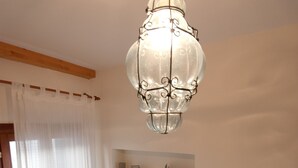 Ein Zimmer mit einer Chandelüstere, Regalen mit Büchern und einem Globus, einem Heizkörper und einem Papierkorb.