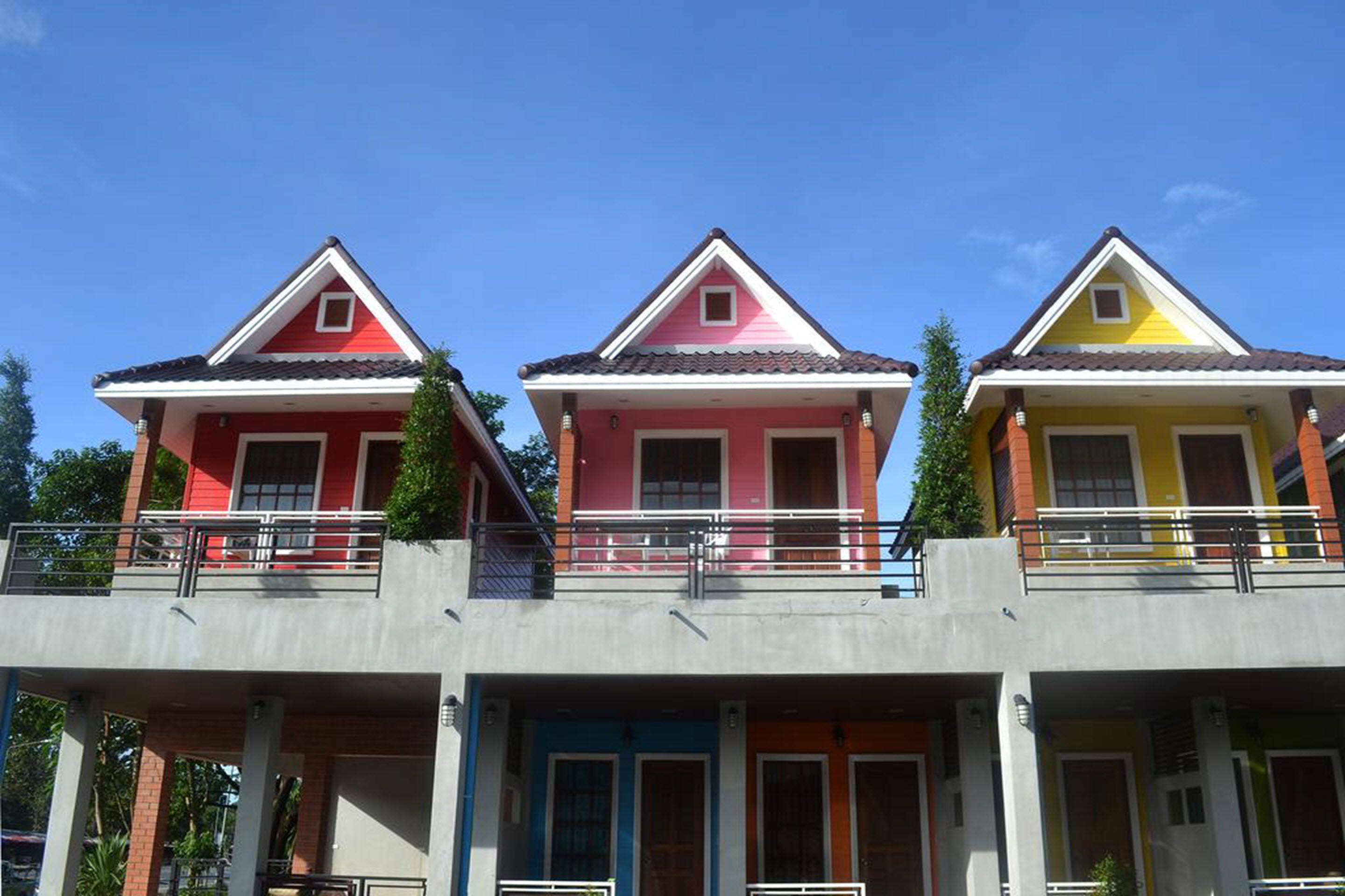 A row of three-story buildings with balconies, each painted in different colors.