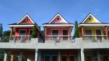 A row of three-story buildings with balconies, each painted in different colors.