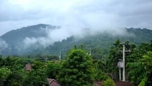 Un paysage montagneux, caractérisé par une végétation luxuriante et quelques bâtiments visibles au premier plan.