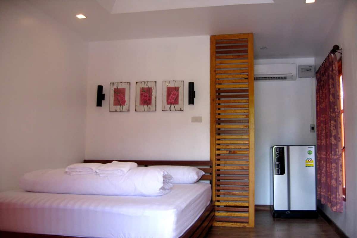 Een hotelkamer met een bed, een houten ladder, een airconditioning en een koelkast.