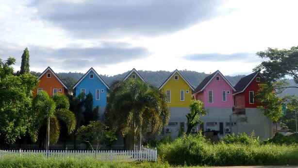 Une rangée de maisons aux couleurs vives, avec une clôture en bois peinte en blanc au premier plan.