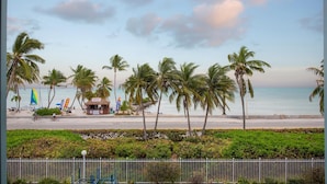 A beach with palm trees, a kiosk, and a clear sky. - 205E La Brisa-2BR 2BA beachfront condo w/parking, shared pool, grills (Key West)