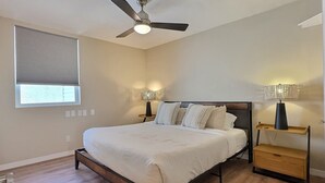 A bedroom with a bed, a ceiling fan, bedside lamps, and a window with blinds. - Siesta Key Beachside Getaway Cottage Walking Distance to Beach and Village (Sarasota)