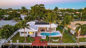 A house with a swimming pool, surrounded by palm trees and a dock. - 5 Bedroom Private Waterfront Villa with Pool and Dock (Fort Lauderdale)