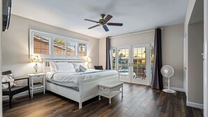 A bedroom with a bed, nightstands, a chair, a window with blinds, a ceiling fan, and a view of the outside. - 5 Bedroom Private Waterfront Villa with Pool and Dock (Fort Lauderdale)