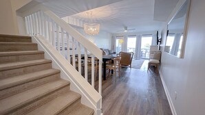 A staircase leading to a dining area with a chandelier, a ceiling fan, and a view of the outdoors. - Relaxing townhouse with beautiful ocean views and just steps to the beach! (Wrightsville Beach)