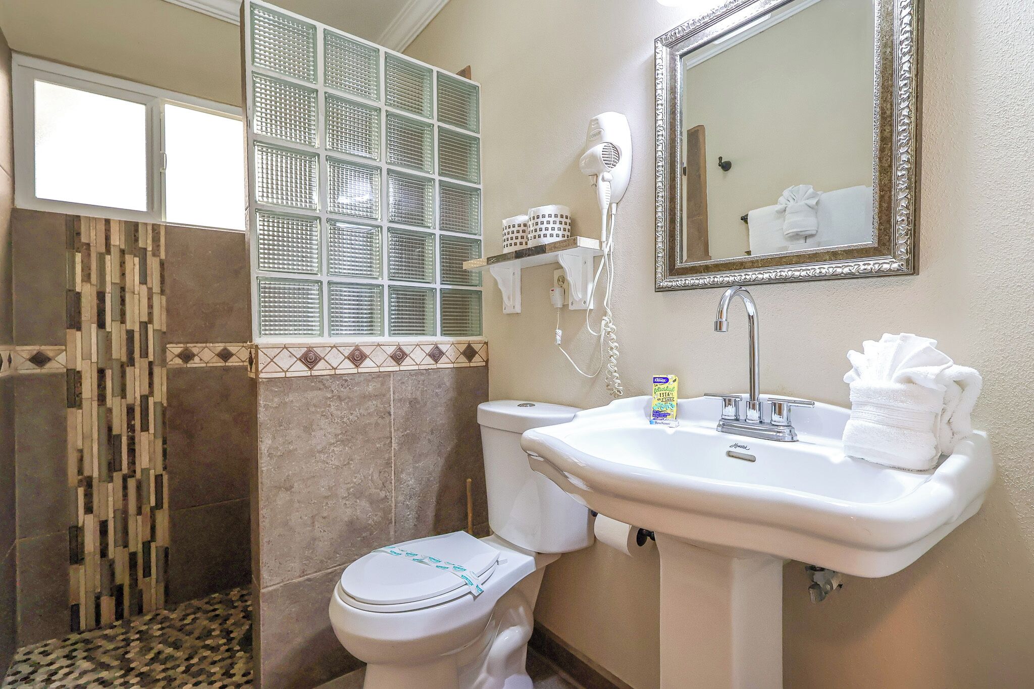 A bathroom with a toilet, sink, and window with blinds.
