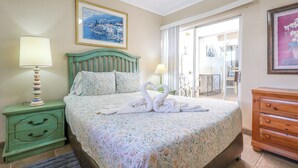 Une chambre à coucher comprenant un lit, deux tables de chevet, une commode, une fenêtre avec des rideaux et un tableau accroché au mur.