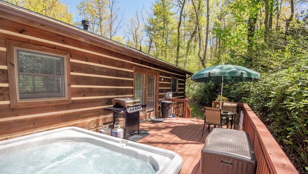 A wooden cabin with a hot tub, outdoor grill, and patio furniture. - Nature Hideout with Great Location | Bear's Den Log Cabin | Hot Tub & Two Decks (Fleetwood)