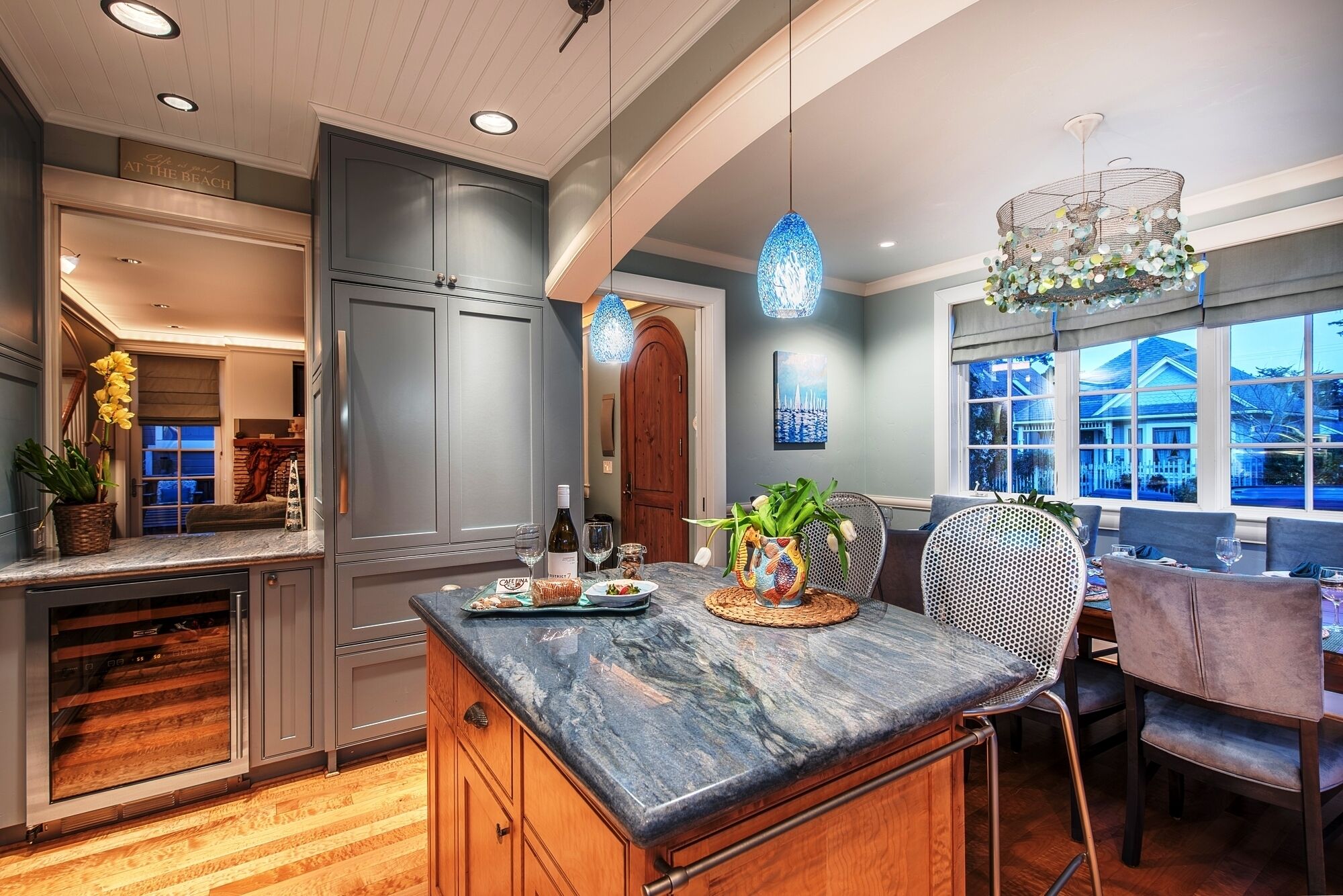 Una cocina moderna con encimera de mármol, armarios de madera y zona de comedor con vistas al exterior.