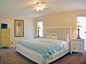 A bedroom with a bed, two bedside tables, a ceiling fan, a window, and a painting on the wall. - Siesta Key Beachside Vacation Rental W/ Heated Pool – Walk to Beach and More (Siesta Key)