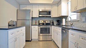 A modern kitchen with stainless steel appliances, white cabinetry, and a tiled backsplash. - Siesta Key Beachside Vacation Rental W/ Heated Pool – Walk to Beach and More (Siesta Key)