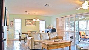 A spacious living area with a sofa, coffee table, and dining table. There is a kitchen area in the background with a refrigerator and cabinets. - Siesta Key Beachside Vacation Rental W/ Heated Pool – Walk to Beach and More (Siesta Key)