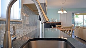 A modern kitchen with a stainless steel faucet, a tiled backsplash, and a black countertop. - Siesta Key Beachside Vacation Rental W/ Heated Pool – Walk to Beach and More (Siesta Key)