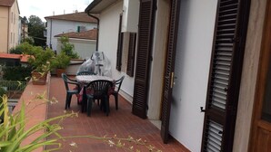 A patio area with a table and chairs, potted plants, and a tiled floor. - Sunny apartment in a residential area, not far from the historic center (Pisa)