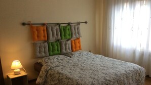 A bedroom with a bed, a nightstand, a lamp, and a window with curtains. - Sunny apartment in a residential area, not far from the historic center (Pisa)