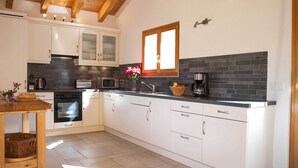 A modern kitchen with white cabinets, a microwave, a coffee maker, and a window. - Chalet le Fauconnier - La Tzoumaz, 4 Vallees (La Tzoumaz)