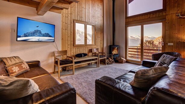 A cozy living room with wooden walls, a fireplace, and a large window offering a mountain view. - Chalet le Fauconnier - La Tzoumaz, 4 Vallees (La Tzoumaz)