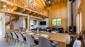 A spacious dining area with a long wooden table, modern chairs, and a cozy fireplace. - Chalet le Fauconnier - La Tzoumaz, 4 Vallees (La Tzoumaz)