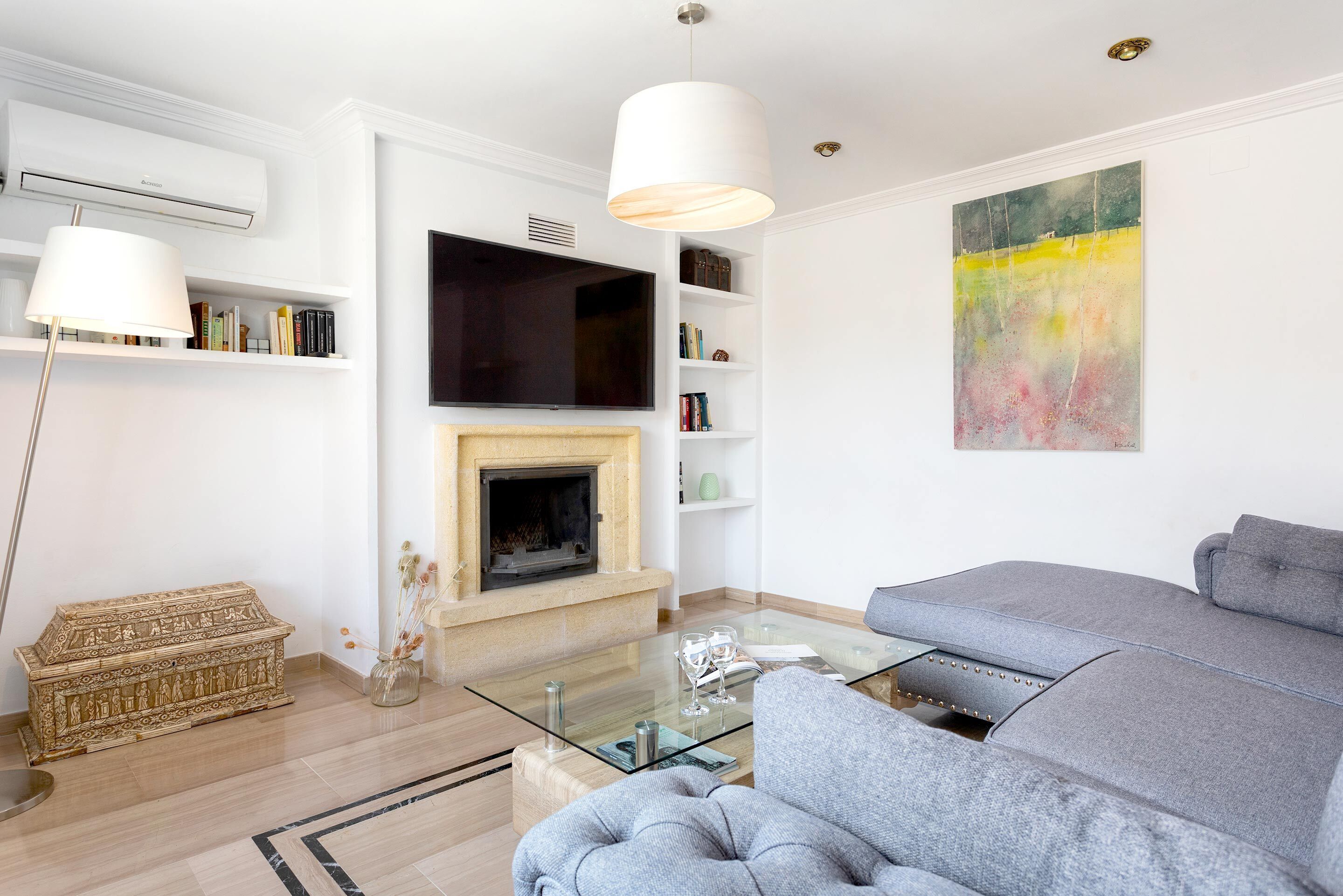 Un salon moderne avec une cheminée, un canapé, une table basse en verre et un téléviseur à écran plat.