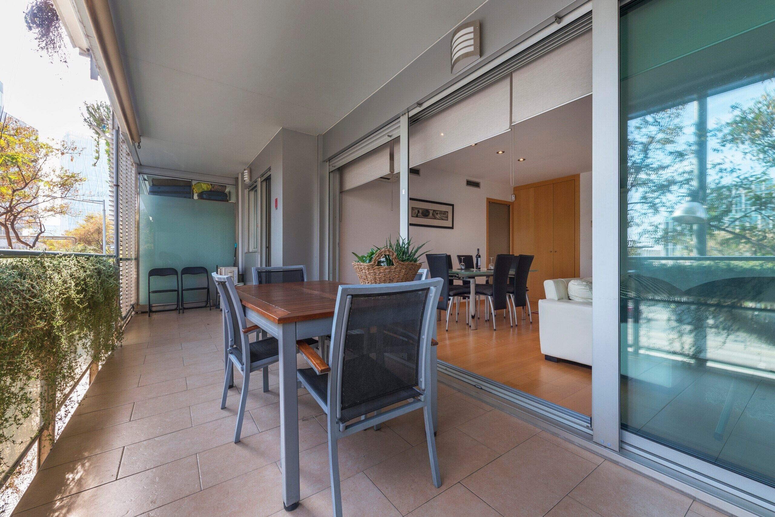 A modern dining area with a wooden table and chairs, a basket of fruit, and a view of the adjacent living space.