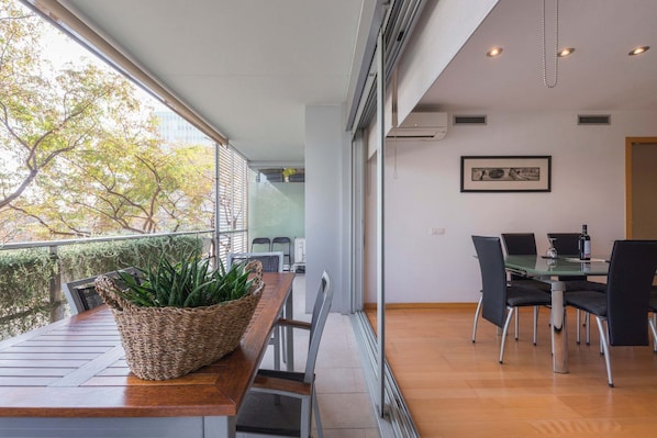 A modern dining area with a glass table, black chairs, and a wicker basket with plants.