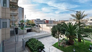 Een woongebouw met balkons, een binnentuin met palmbomen en een kraan op de achtergrond.