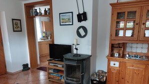 A living room with a TV, wooden cabinets, a fireplace, and a tiled floor.