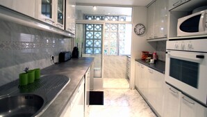 Une cuisine moderne avec des meubles blancs, un évier en acier inoxydable et un four à micro-ondes.