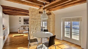 Un comedor con una mesa redonda y sillas, una pared de piedra y una ventana con persianas.