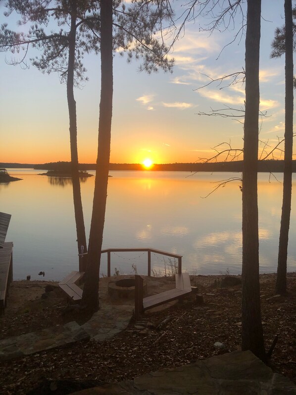 A serene lakeside view with a sunset, surrounded by trees and a wooden structure with a bench. - Big Water View- Lake Martin-Sunset Station! (Dadeville)