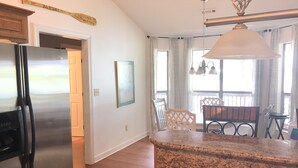 A kitchen with a stainless steel refrigerator, a granite countertop, and a dining area with a table and chairs.