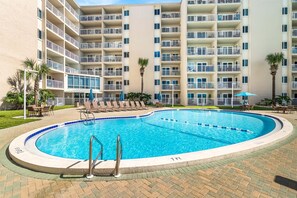 Un hôtel doté d’une piscine entourée de chaises longues et de parasols.