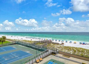 Un court de tennis avec vue sur la plage et l’océan.