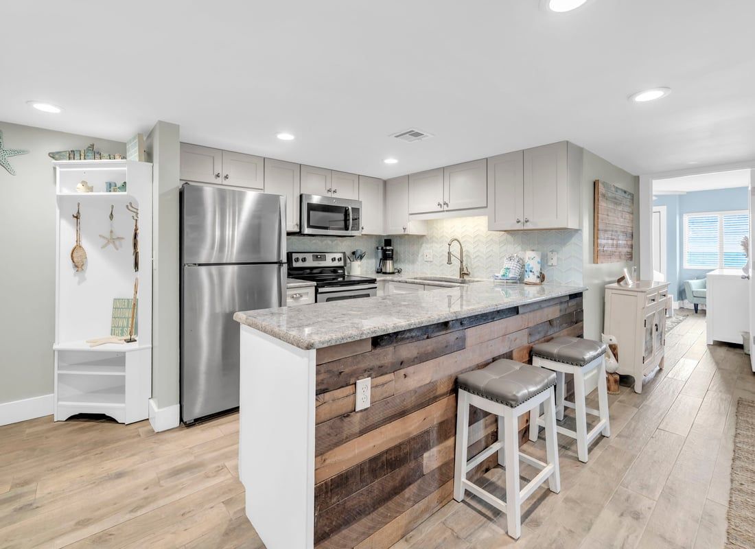 A modern kitchen with a central island, stainless steel appliances, and a wooden accent wall.