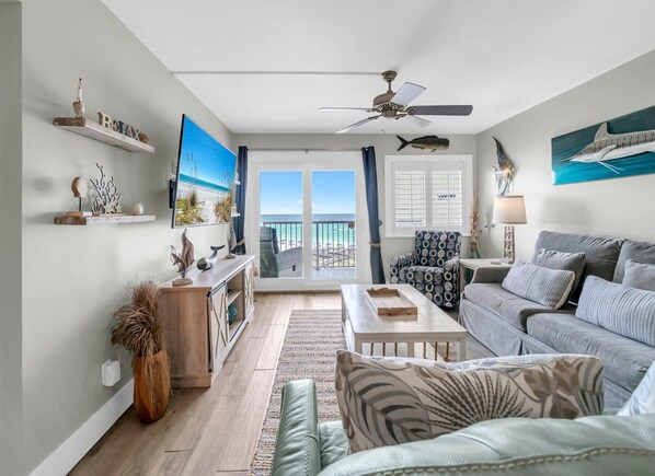 A living room with a sofa, a coffee table, a TV, and a ceiling fan.
