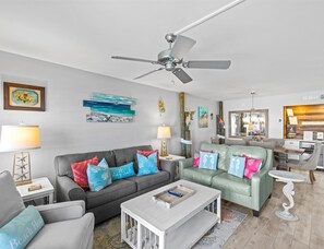 A modern living room with a grey sofa, a green sofa, and a white coffee table. There is a ceiling fan, a lamp, and a painting on the wall. - 404-mWelcome to Paradise beautifully remodeled Beachfront condo (Destin)