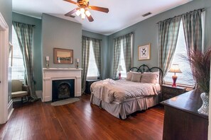 Une chambre à coucher avec une cheminée, un lit, une table de chevet et une chaise.