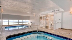 An indoor swimming pool with a view of the ocean through large windows.