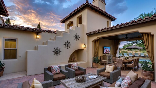 A patio area with wicker furniture, a wooden table, and a TV screen. - Cappella - Gorgeous 4 br Villa in PGA West with Pool/Spa + Golf Course Views #259222 (La Quinta)